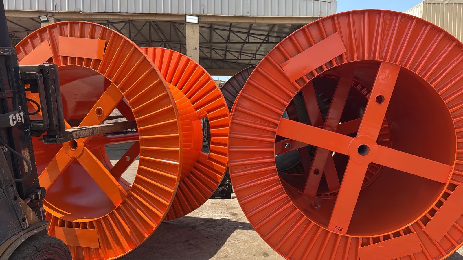 Orange steel cable drums lined up in the yard